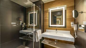 Een moderne badkamer met dubbele wastafels, een douchecabine met glazen wanden en een wastafelmeubel met spiegel.