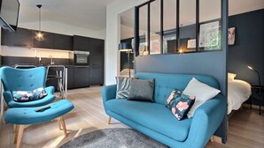 Ein modernes Wohnzimmer mit einem blauen Sofa, einem passenden Sessel und einem kleinen Rundteppich.