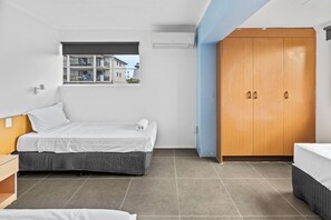 A bedroom with a bed, a wardrobe, a window with a view, and a ceiling fan.