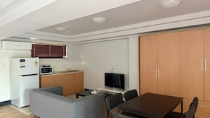Un espace de vie compact comprenant une kitchenette, un coin repas et un téléviseur.