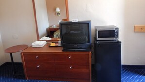 A hotel room with a wooden dresser, a television, and a microwave. - Bay Bridge Inn (Oakland)