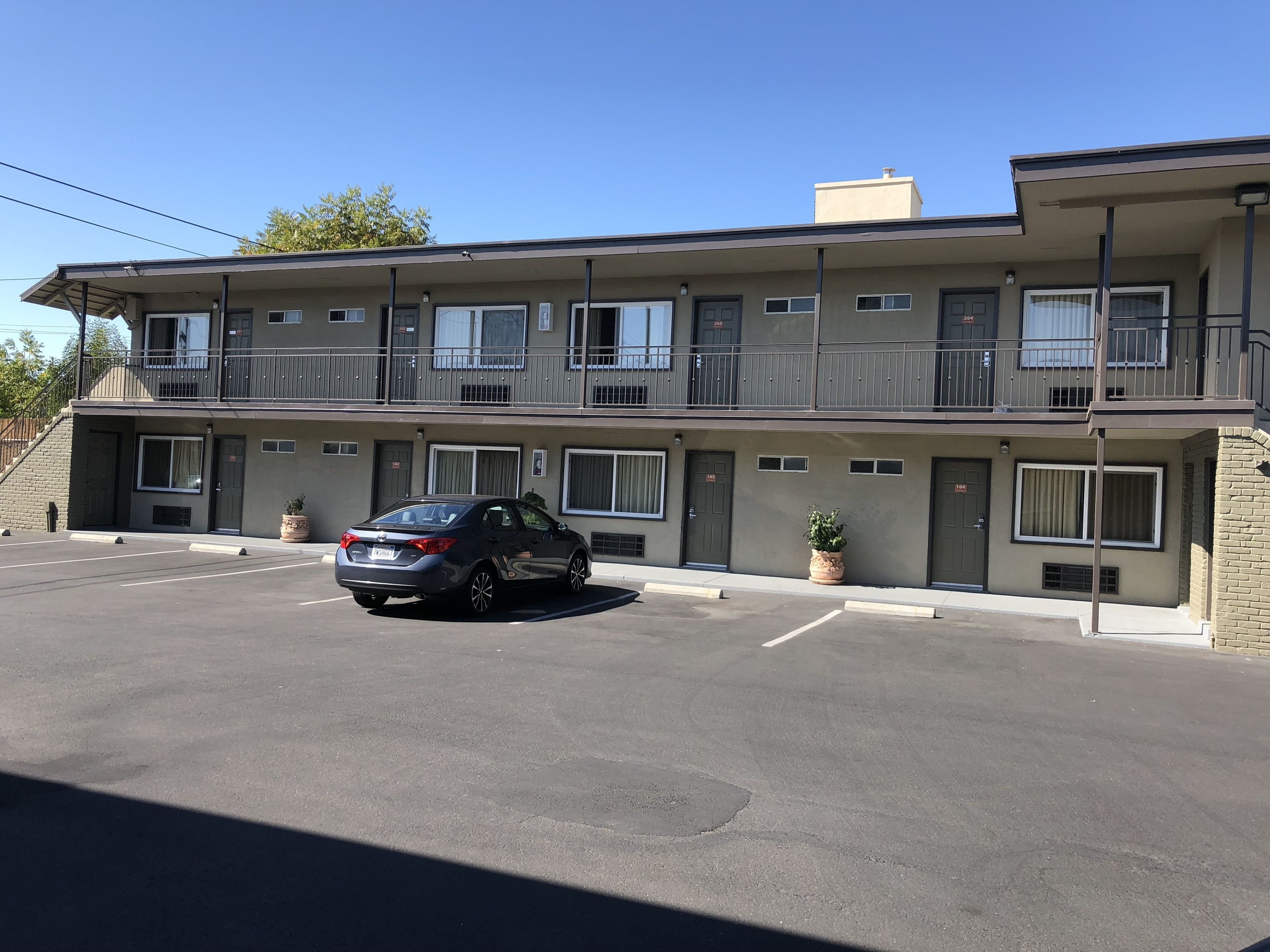 A two-story motel with a car parked in the driveway.