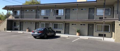 A two-story motel with a car parked in the driveway.