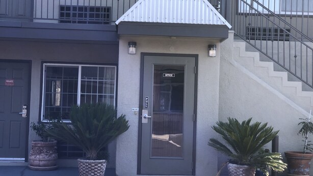 A building with a gated entrance, a sign indicating an office, and a staircase leading to an upper level. - Bay Bridge Inn (Oakland)