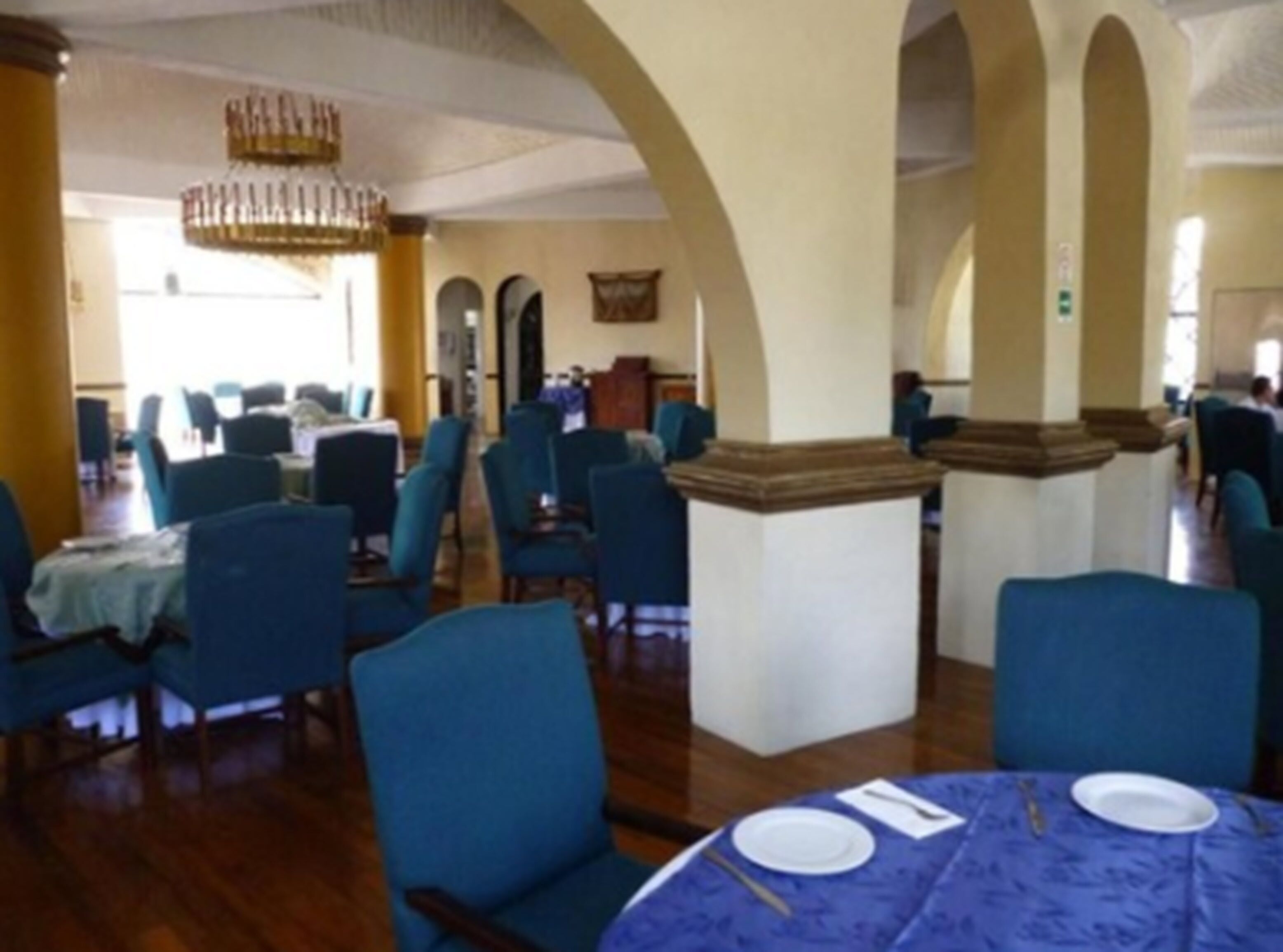 A dining area with round tables, blue chairs, and a chandelier.