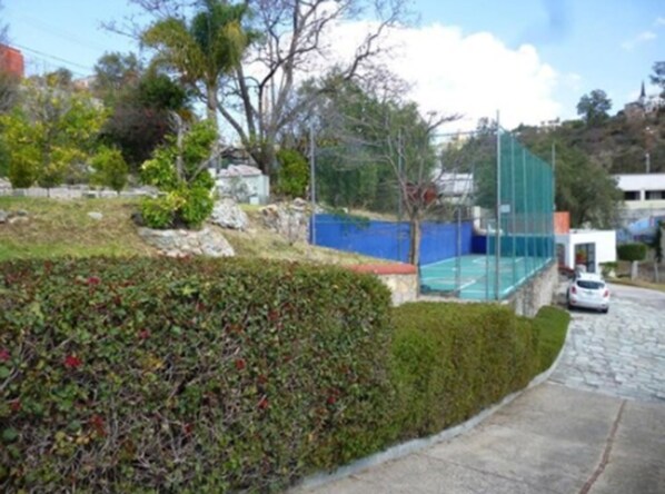 A residential area with a tennis court, a car parked on the street, and a hedge along the sidewalk. - Hotel Castillo Santa Cecilia (Guanajuato)