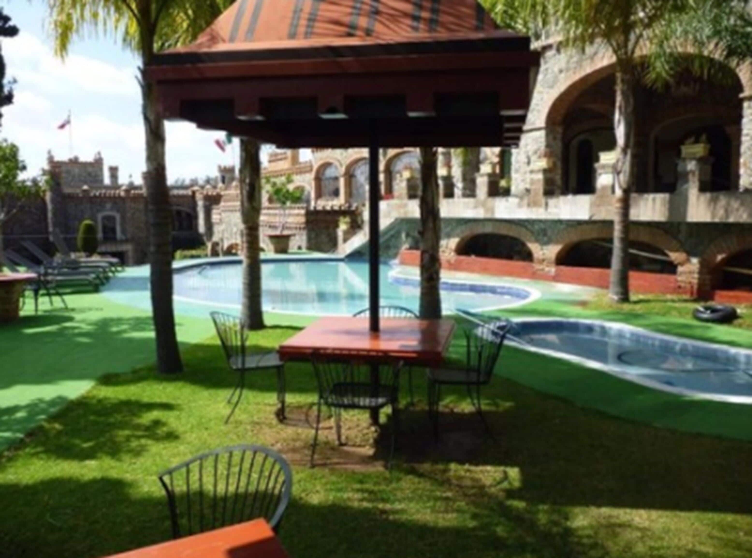 A pool area with a gazebo, outdoor seating, and stone architecture.