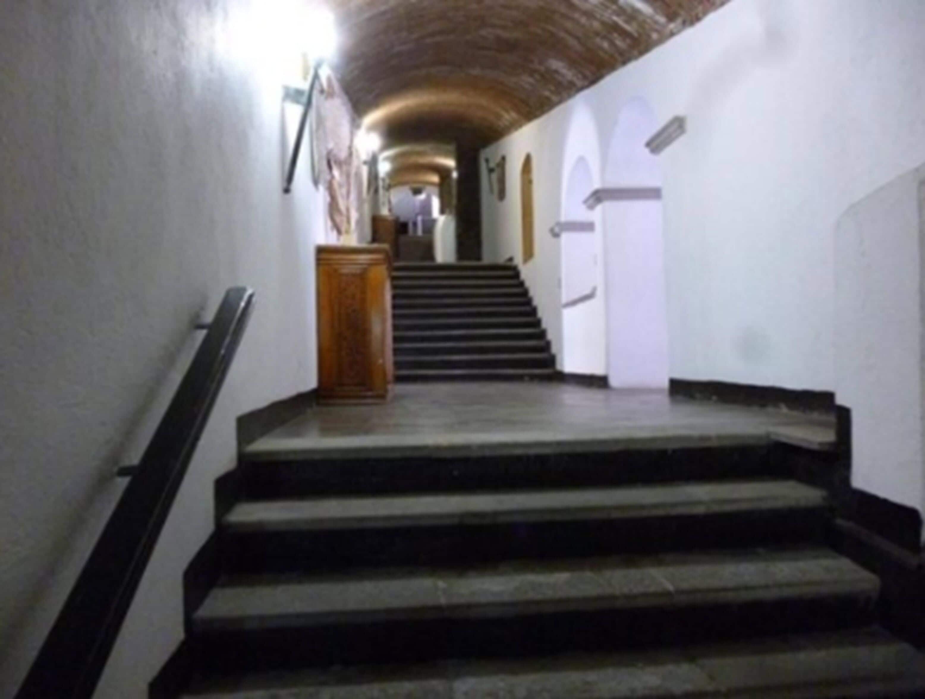 Una scala conduce a un pianerottolo con un podio in legno e una porta bianca.