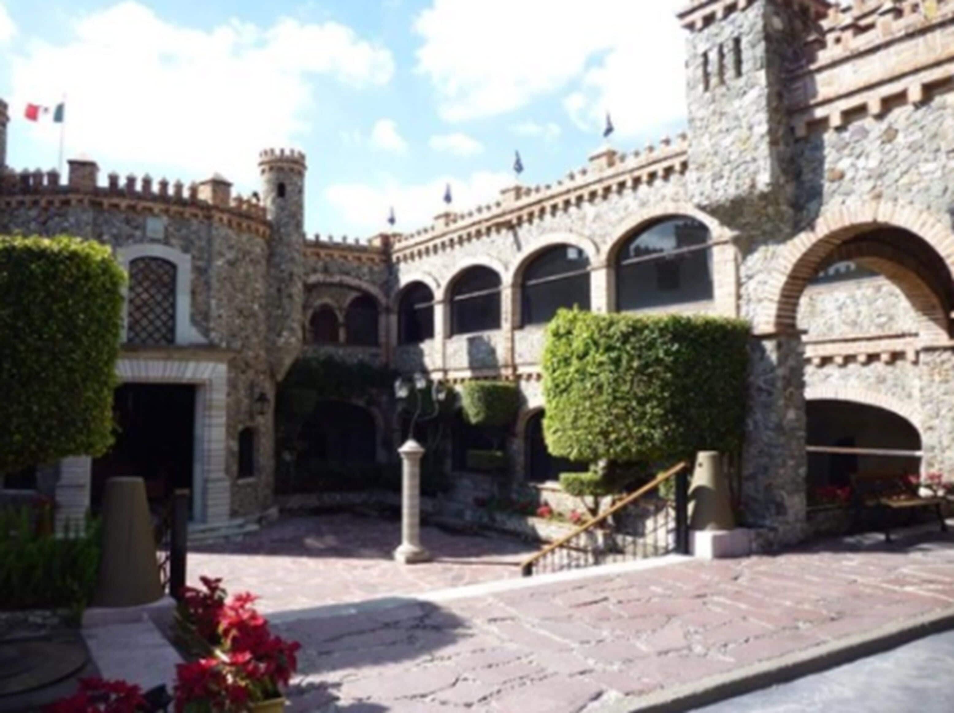 A courtyard with stone architecture, arched doorways, and a central staircase.