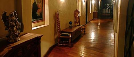 A wooden hallway with a bench, a statue, and a framed picture on the wall.