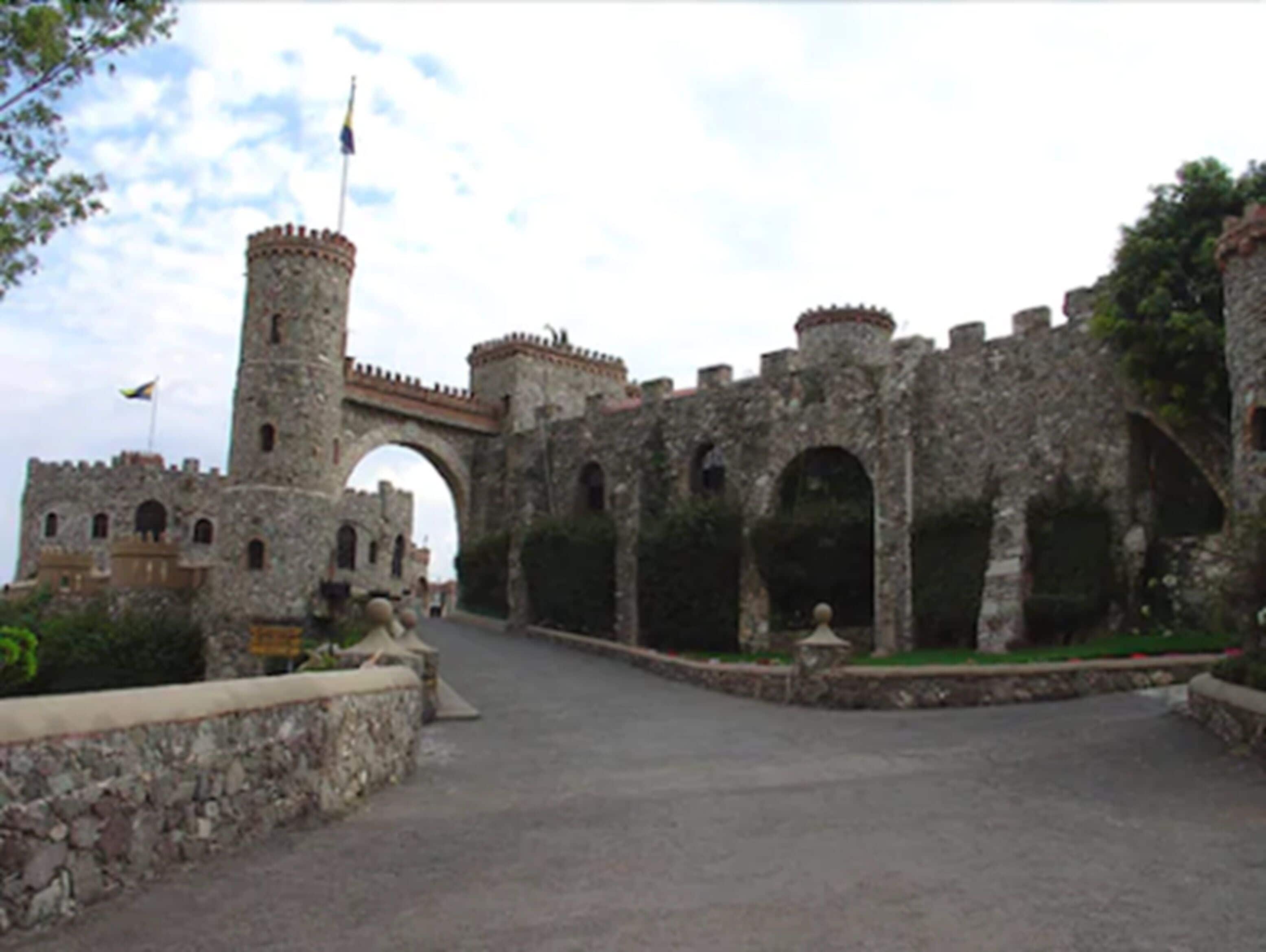 An old stone castle with a large archway and a flag on top of a tower.