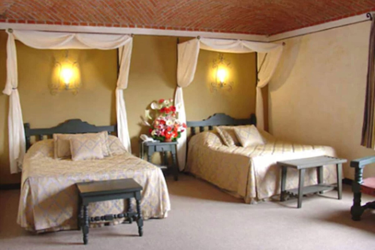 A room with two beds, a bench, and a table.