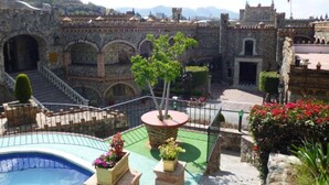 A courtyard with a swimming pool, stone buildings, and a flag.