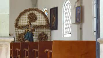 Interior de iglesia con bancos de madera, una estatua y pinturas religiosas.