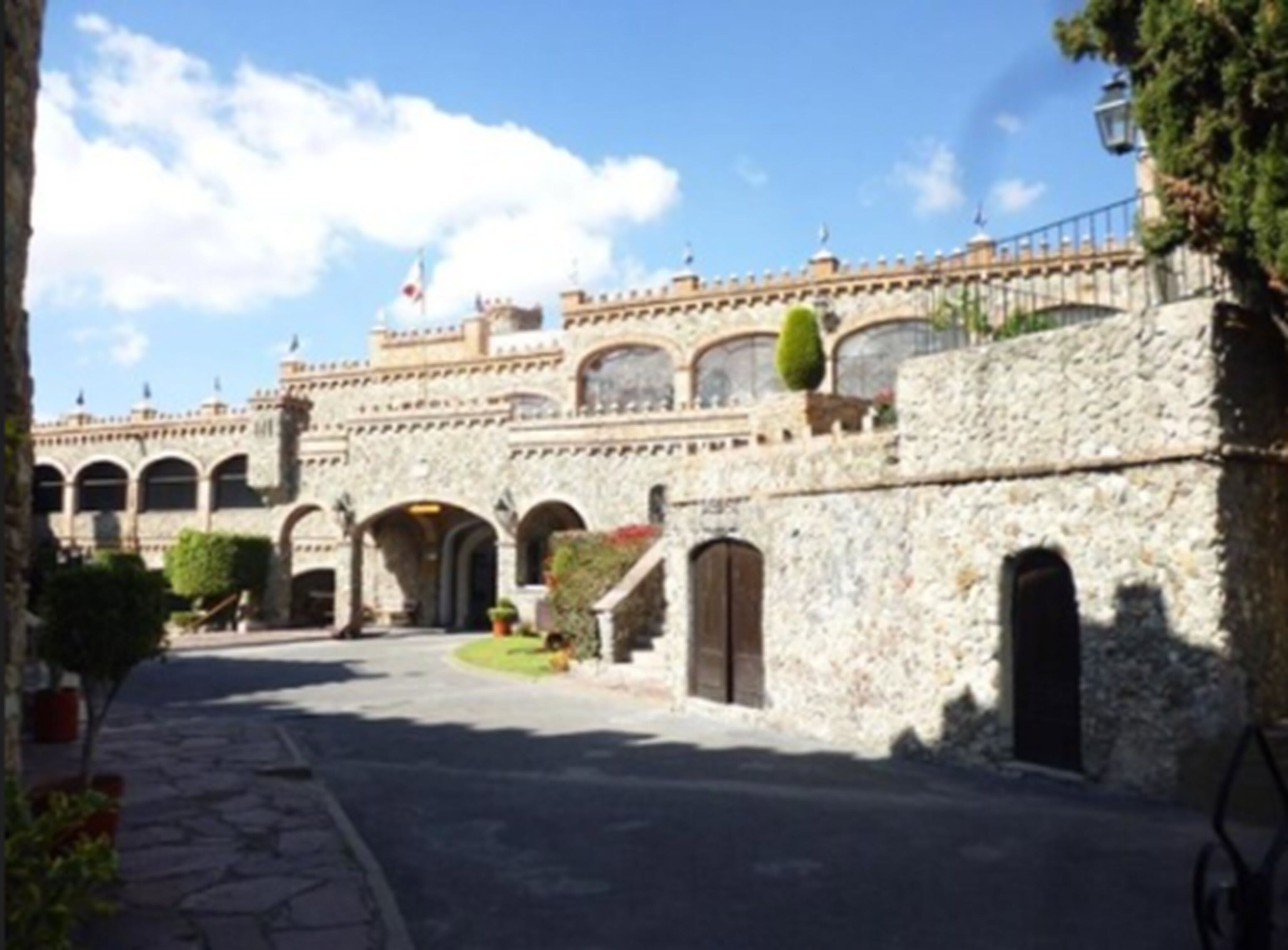 Un edificio histórico de piedra con ventanas arqueadas y un patio central.
