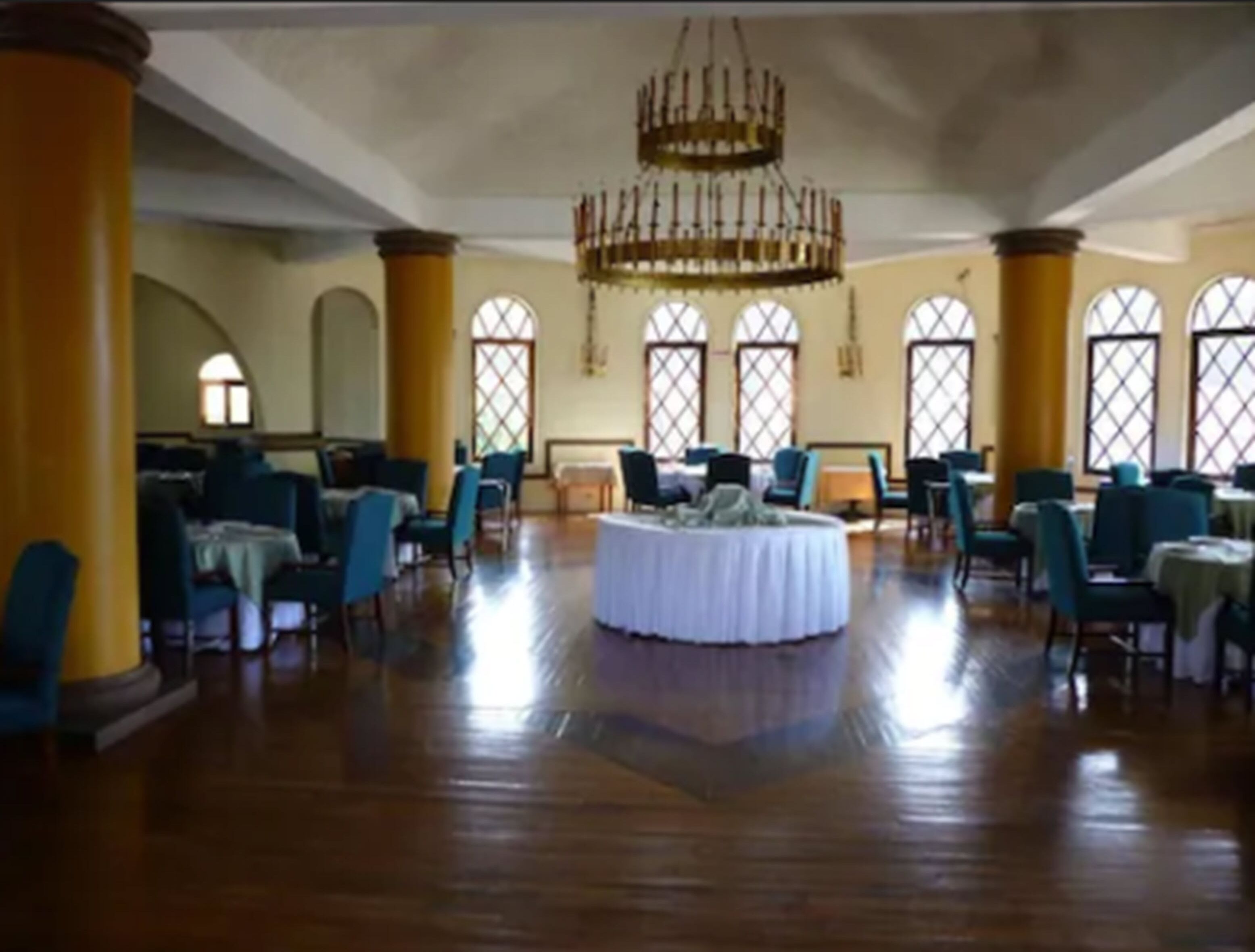 A spacious hall with high ceilings, large windows, and a central chandelier.