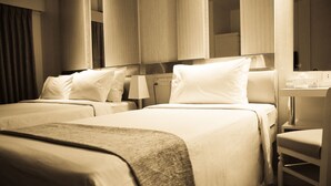A hotel room with two beds, a bedside table, a lamp, and a mirror. - Hotel Ornate (Dhaka)