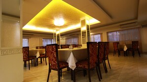 A dining area with a central round table surrounded by chairs, a ceiling light fixture, and a tiled floor. - Hotel Ornate (Dhaka)