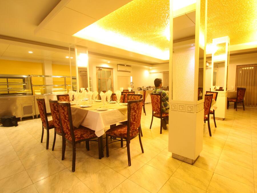 A dining area with a large table set for a meal, surrounded by chairs with patterned upholstery.