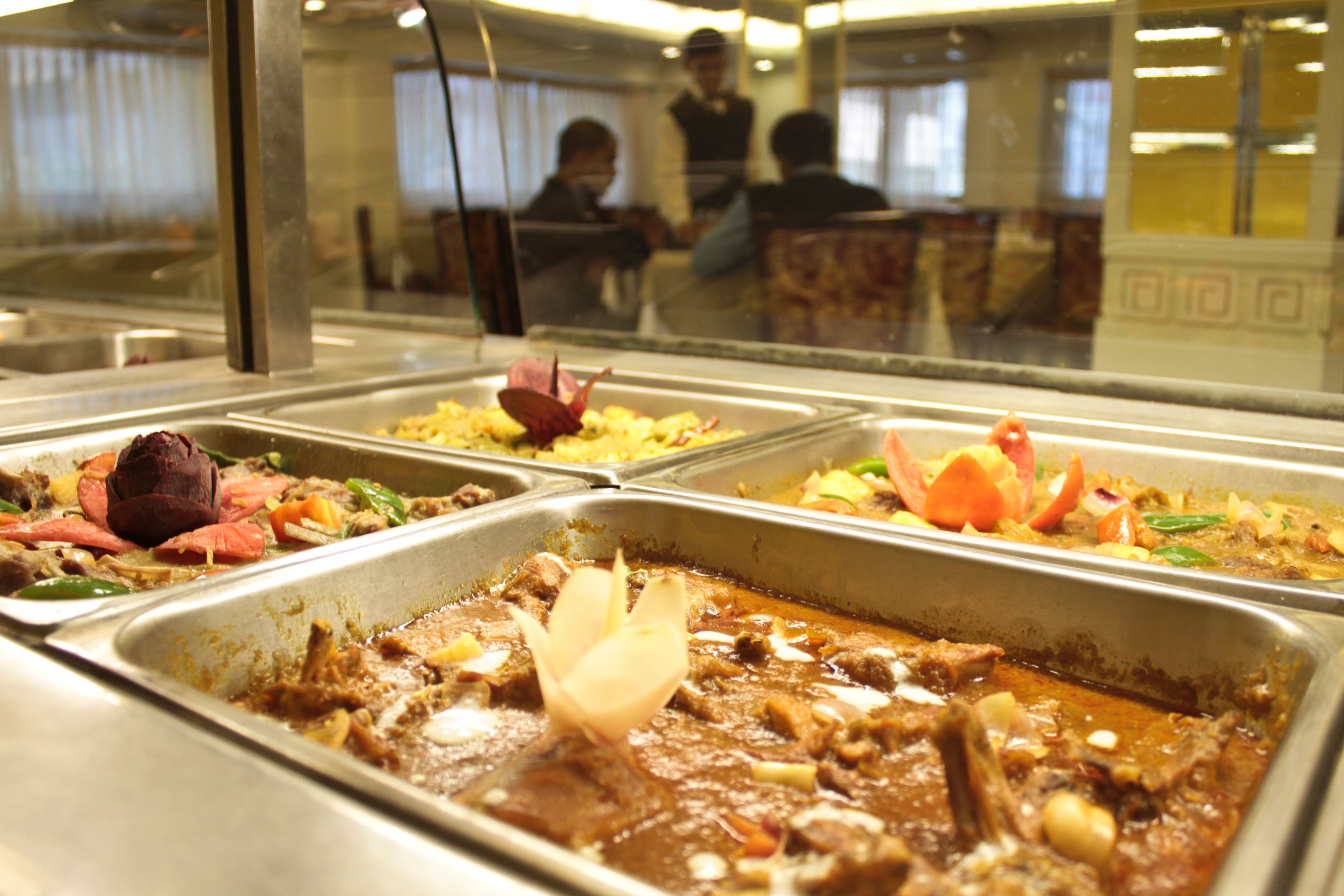 A buffet with various dishes including meat, vegetables, and rice.