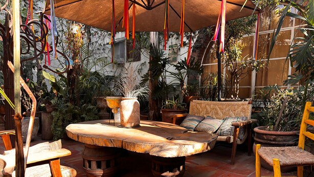 A rustic outdoor seating area with a wooden table, chairs, and a hanging chair. - Casa Tlaquepaque (Tlaquepaque)