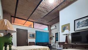 A hotel room with a large bed, a television, a lamp, and a ceiling with exposed brickwork. - Casa Tlaquepaque (Tlaquepaque)