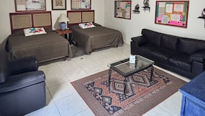 A room with a brick ceiling, two beds, a black sofa, a coffee table, and a patterned rug. - Casa Tlaquepaque (Tlaquepaque)