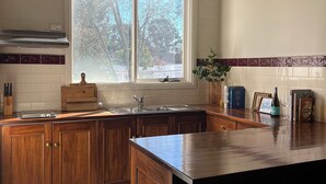 Eine Küche mit Holzausstattung, einer Edelstahl-Spüle und einem Fenster mit Blick auf Bäume.