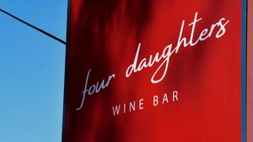 A red sign with 'four daughters' and 'WINE BAR' written on it.