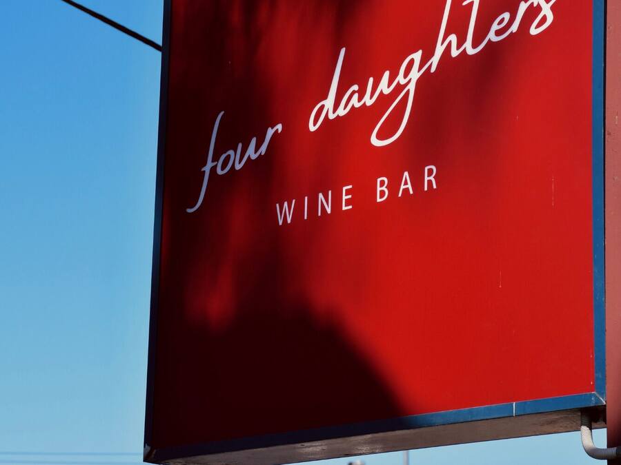 A red sign with 'four daughters' and 'WINE BAR' written on it.