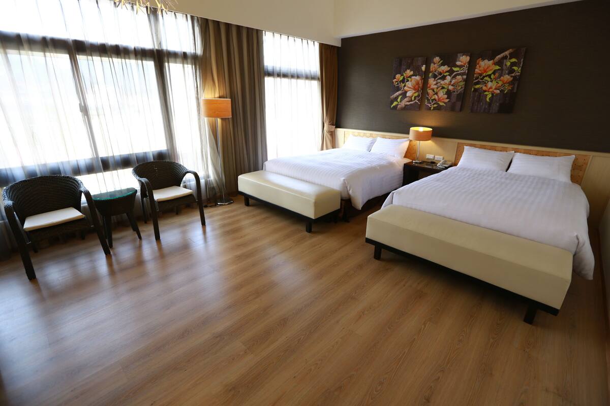 A hotel room with two beds, a desk, and a chair.