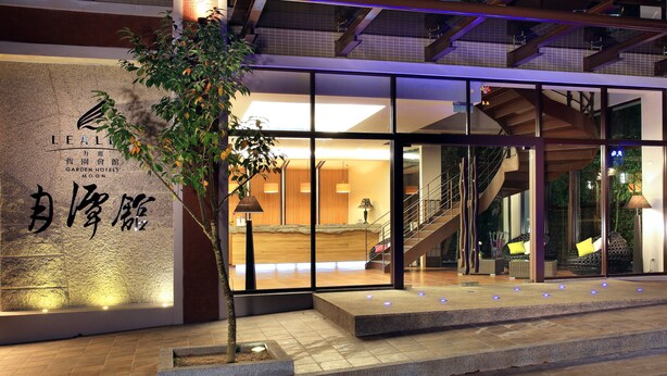 The exterior of the Leale Garden Hotel Moon with a modern design, including a staircase and a reception area visible through the glass doors. - Lealea Garden Hotel Moon (Yuchi)