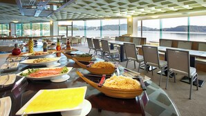 A buffet setup with various dishes and a scenic view of a lake through large windows. - Lealea Garden Hotel Moon (Yuchi)