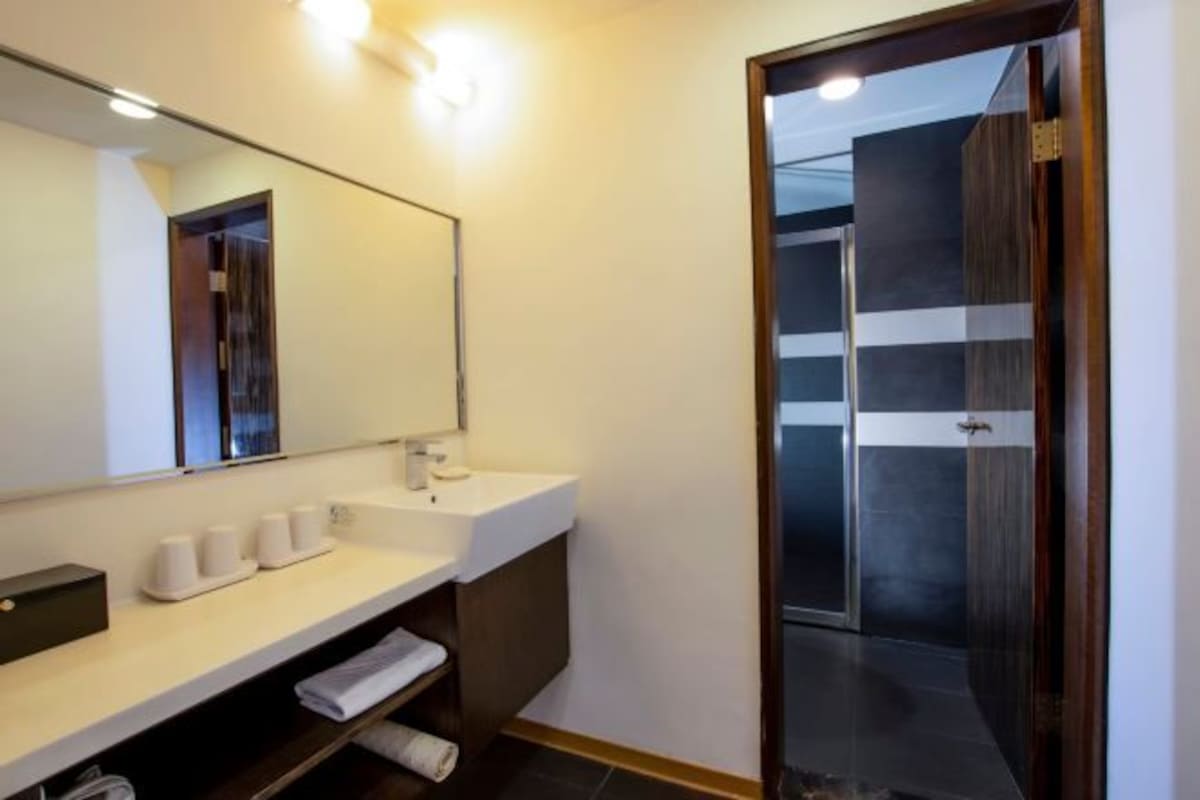 Un baño moderno con un espejo grande, un lavabo blanco y una zona de ducha.