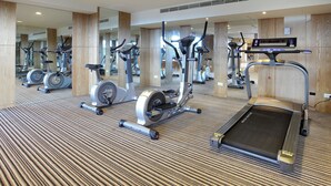 A gym with various exercise machines, a mirrored wall, and a carpeted floor. - Lealea Garden Hotel Moon (Yuchi)