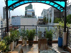 A rooftop terrace with potted plants, a table, and chairs. - Kim Hotel (Ho Chi Minh City)