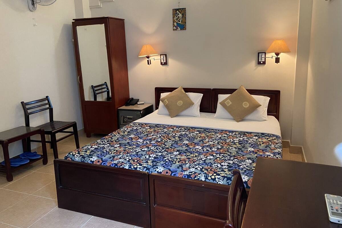Une chambre d’hôtel avec un grand lit, deux lampes de chevet, une table de chevet, une chaise, un bureau et un miroir.