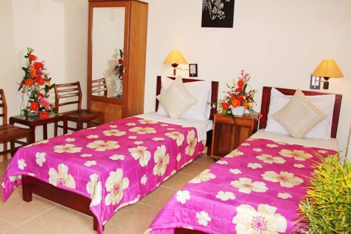 Une chambre d’hôtel avec deux lits, des meubles en bois et des décorations florales.