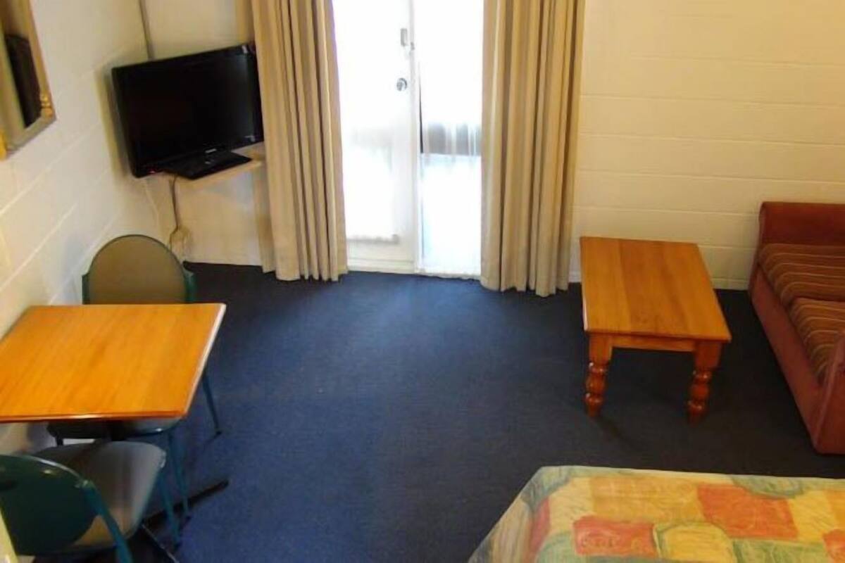 A room with a bed, a desk, a chair, a television, and a couch.