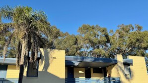 A building with a yellow facade, a blue staircase, and a palm tree in the foreground. - Pathfinder Motel (Kew)