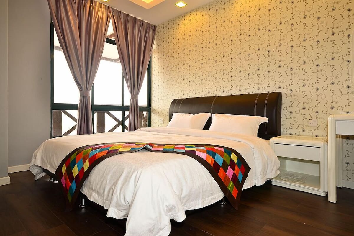A neatly arranged bedroom with a large bed, a nightstand, and a window with curtains.
