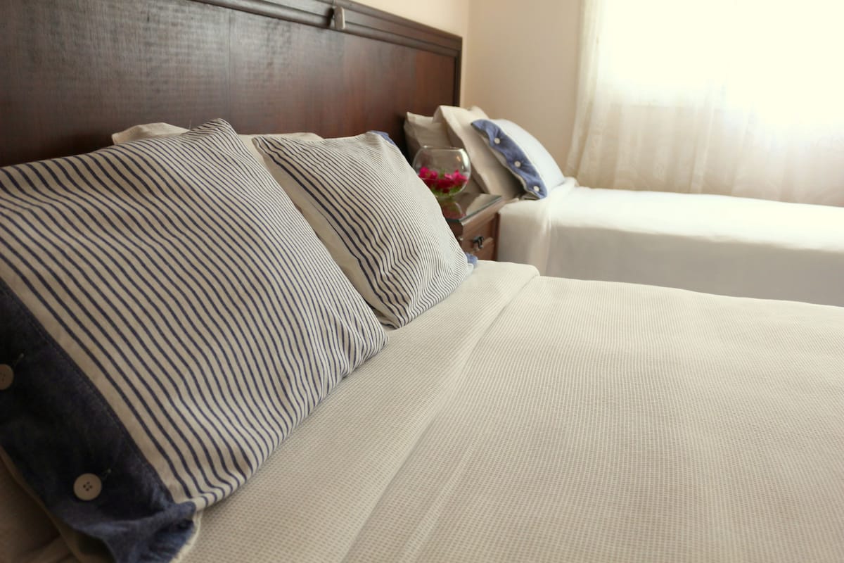 A hotel room with a large bed, a nightstand, and a bedside table with a vase of flowers.
