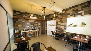 A restaurant with a stone wall, wooden tables, and black chairs. - Hotel Playa Brava (Punta del Este)