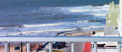A view of the sea from a balcony with a street in the foreground.