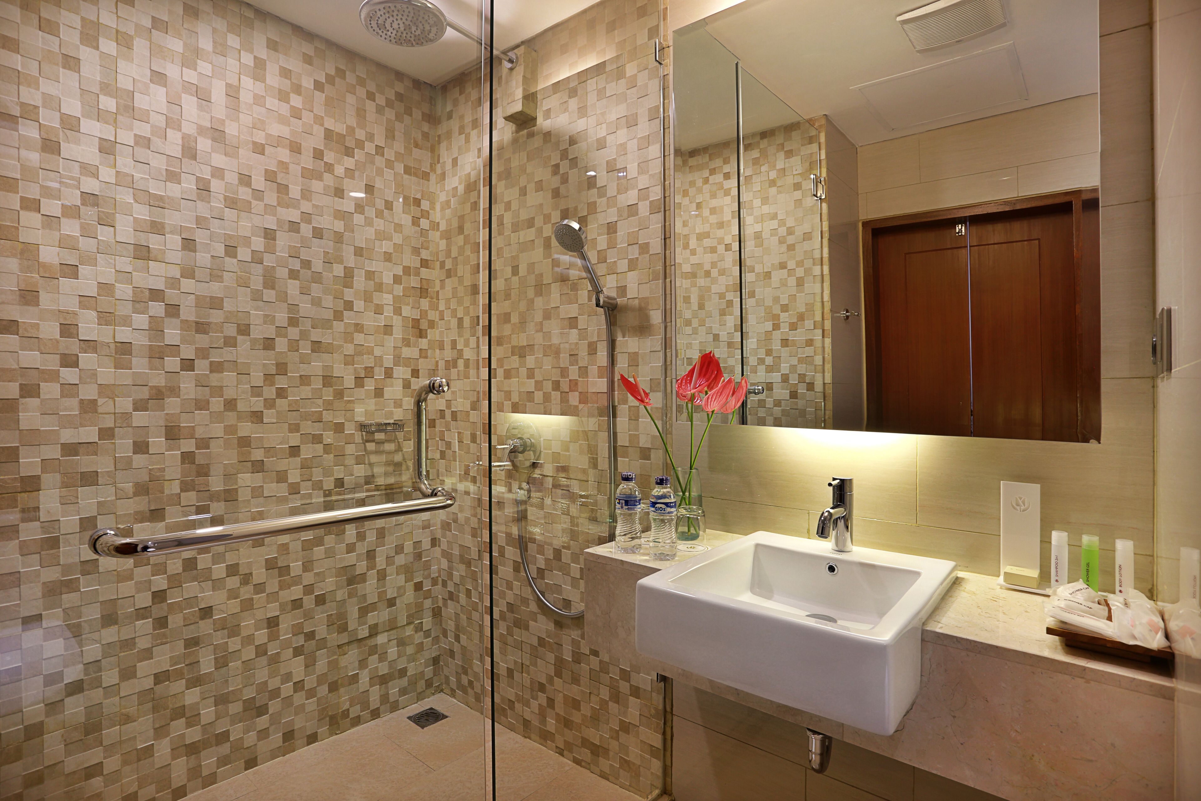 A modern bathroom with a glass shower enclosure, a white sink, and a mirror above it.