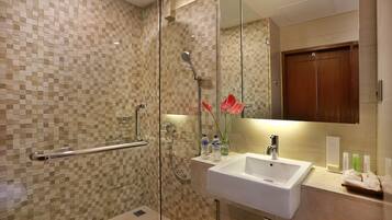 A modern bathroom with a glass shower enclosure, a white sink, and a mirror above it.