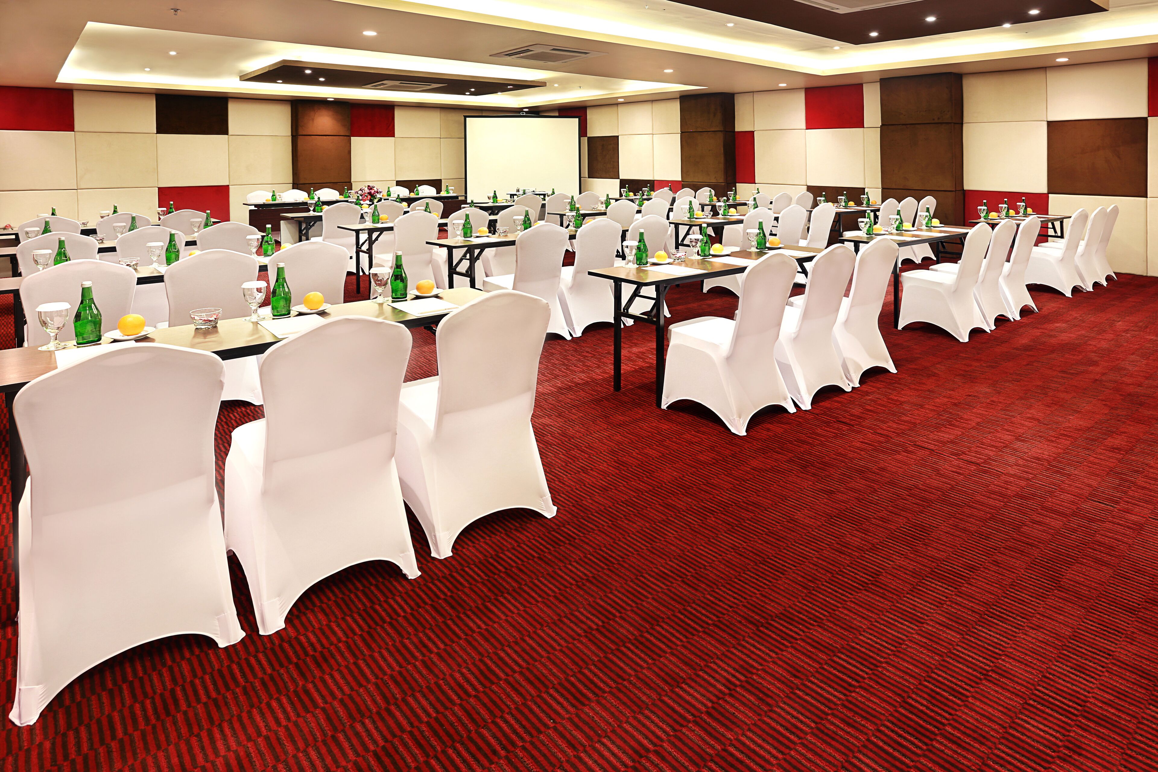 A conference room with multiple tables and chairs, equipped with water bottles and glasses.