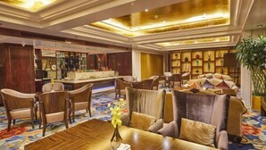 A hotel lobby with a bar area, seating arrangements, and a decorative ceiling.