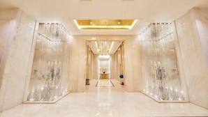 A spacious, well-lit hallway with marble walls and a central light fixture.
