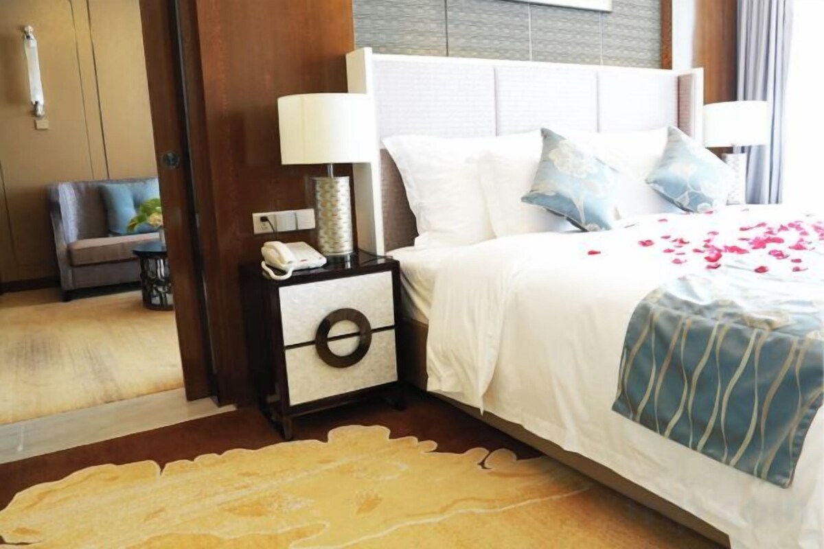 Une chambre d’hôtel avec un lit, des tables de chevet, une lampe et un tapis.